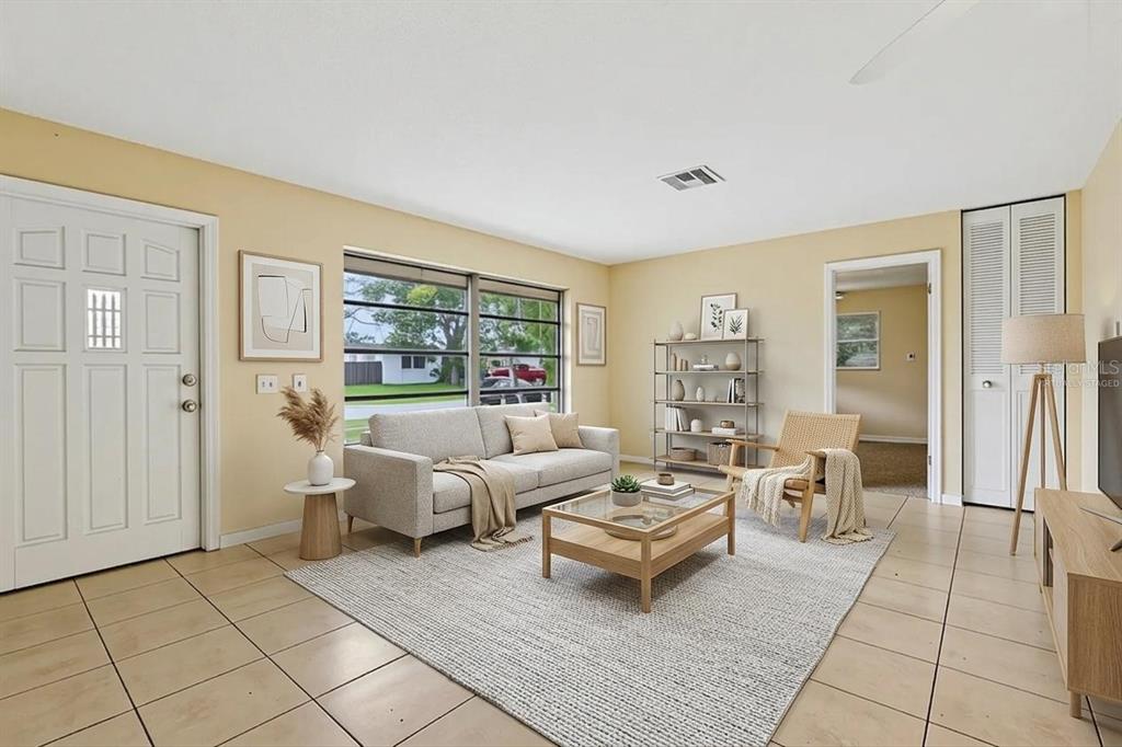 A living room with beige tile floors, a gray sofa, and a glass-topped coffee table — 1806 DODGE CIRCLE, MELBOURNE, FL