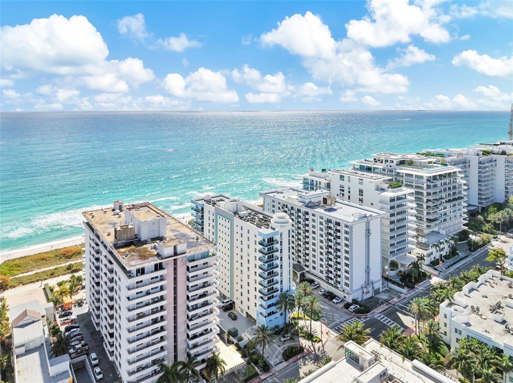 An aerial view shows several high-rise apartment buildings located along a sandy beach and ocean — 9201 COLLINS AVENUE UNIT 821, SURFSIDE, FL