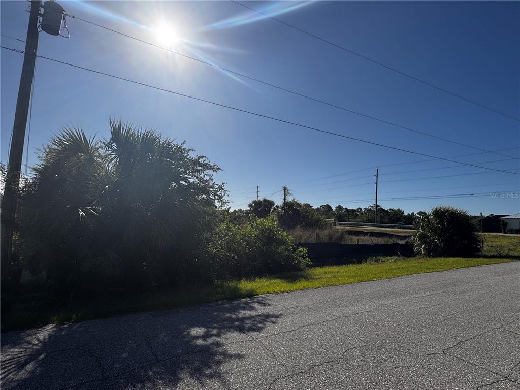 A view of a vacant, grassy lot with trees and power lines under a sunny sky — 14270 SAN DOMINGO BOULEVARD, PORT CHARLOTTE, FL