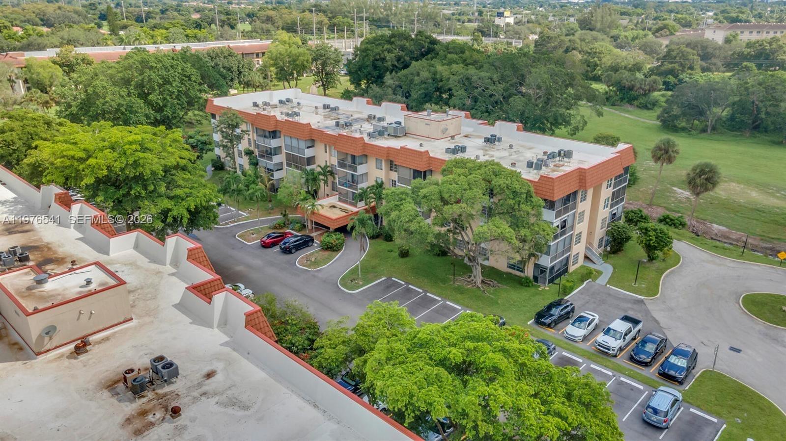 An aerial view shows a multi-story apartment building surrounded by trees and parking lots — 4166 Inverrary Dr # 410, Lauderhill FL 33319, LAUDERHILL, FL