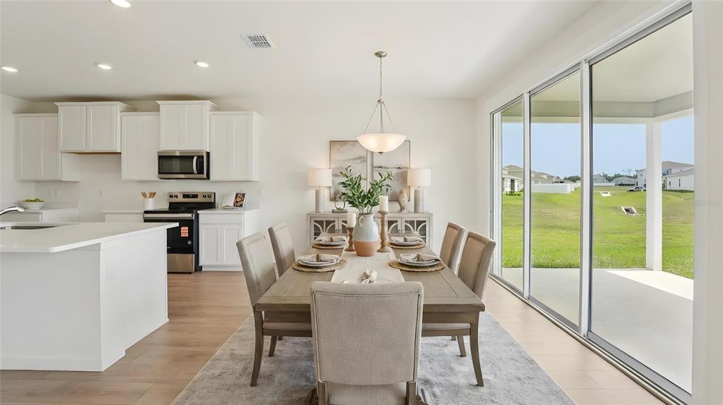 A dining area with a wooden table and chairs sits adjacent to a white kitchen — 17979 NW 172ND AVENUE, ALACHUA, FL
