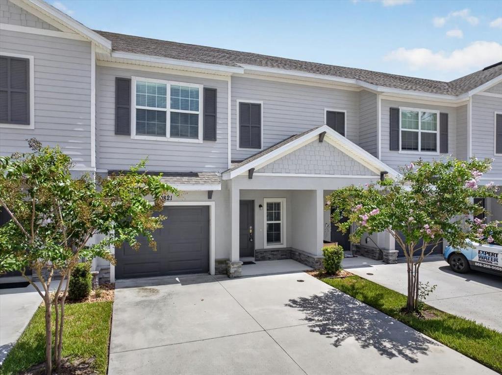 A two-story townhouse exterior with gray siding, a single-car garage, and a covered entryway — 10821 QUICKWATER COURT, RIVERVIEW, FL