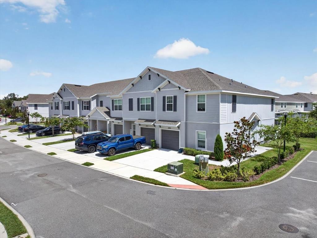 An exterior view of a multi-unit townhouse building with gray siding and attached garages — 10821 QUICKWATER COURT, RIVERVIEW, FL