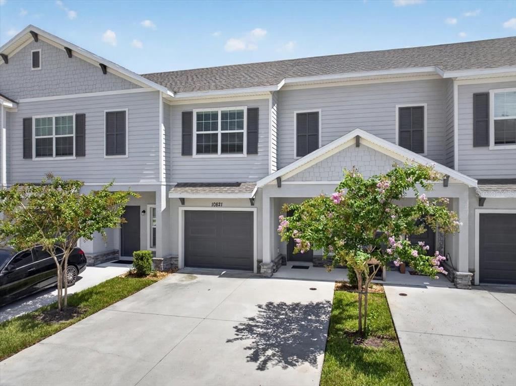 A two-story townhouse with light gray siding, a garage, and a concrete driveway — 10821 QUICKWATER COURT, RIVERVIEW, FL