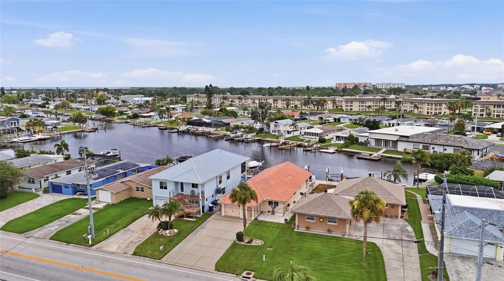 An aerial view shows waterfront houses with docks along a canal near a road — 4549 TOPSAIL TRAIL, NEW PORT RICHEY, FL