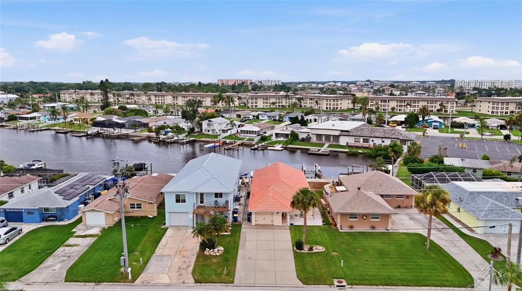 An aerial view shows several waterfront houses with driveways and lawns along a canal — 4549 TOPSAIL TRAIL, NEW PORT RICHEY, FL