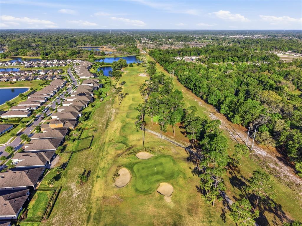 An aerial view shows a golf course green with sand traps adjacent to residential homes — 262 NORTHCOTE COURT, DELAND, FL