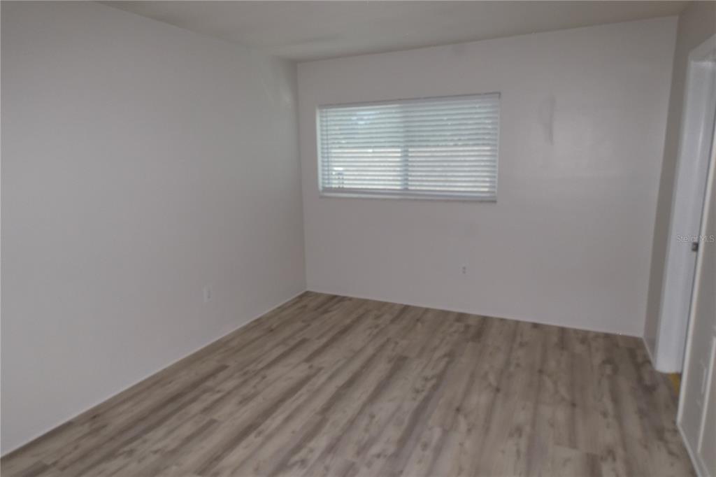 An empty room features light-colored walls, wood-look laminate flooring, and a doorway leading elsewhere — 810 TYRONE BOULEVARD N UNIT G-2, ST PETERSBURG, FL