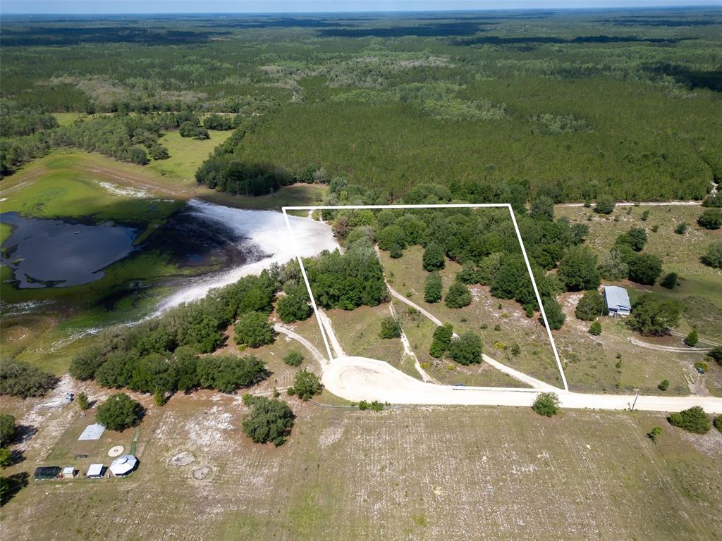 An aerial view shows a vacant, partially wooded lot outlined in white near a pond — SE 53 COURT, TRENTON, FL