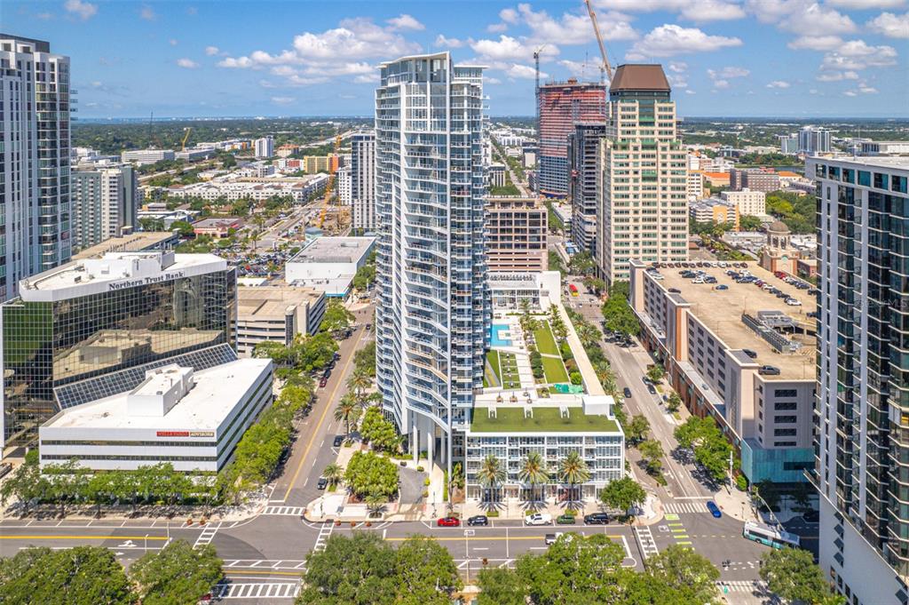 An aerial view of a modern high-rise apartment building surrounded by city streets and buildings — 175 1ST STREET S UNIT 1204, ST PETERSBURG, FL