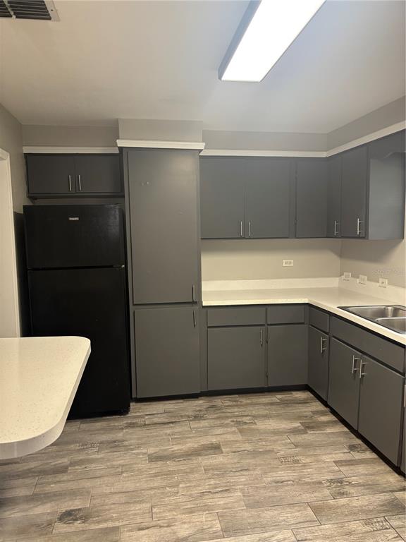 A kitchen features gray cabinets, a black refrigerator, white countertops, and wood-look tile flooring — 807 E OSBORNE AVENUE, TAMPA, FL