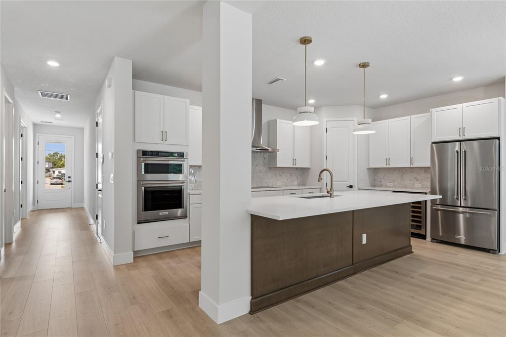 A modern kitchen features white cabinets, a dark wood island, stainless steel appliances, and light flooring — 2916 W ELLIS DRIVE, TAMPA, FL