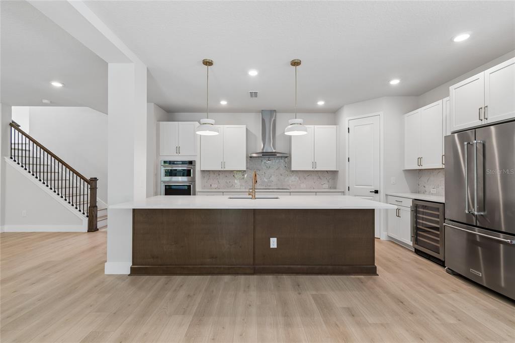 A modern kitchen features white cabinets, a dark wood island, and light wood flooring — 2916 W ELLIS DRIVE, TAMPA, FL