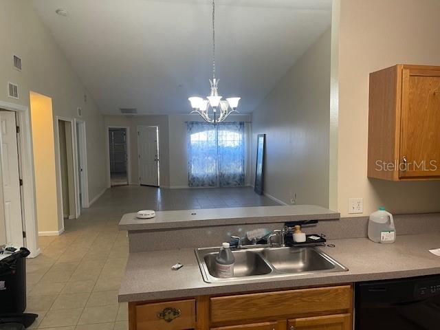 A kitchen sink overlooks an open-concept living area with a chandelier and tile flooring — 38 PINE HURST LANE UNIT B, PALM COAST, FL