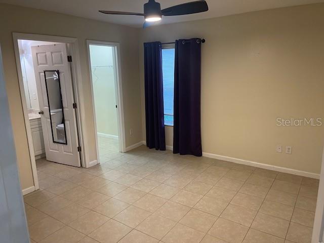 A bedroom with tile flooring, a ceiling fan, purple curtains, and two doorways — 38 PINE HURST LANE UNIT B, PALM COAST, FL