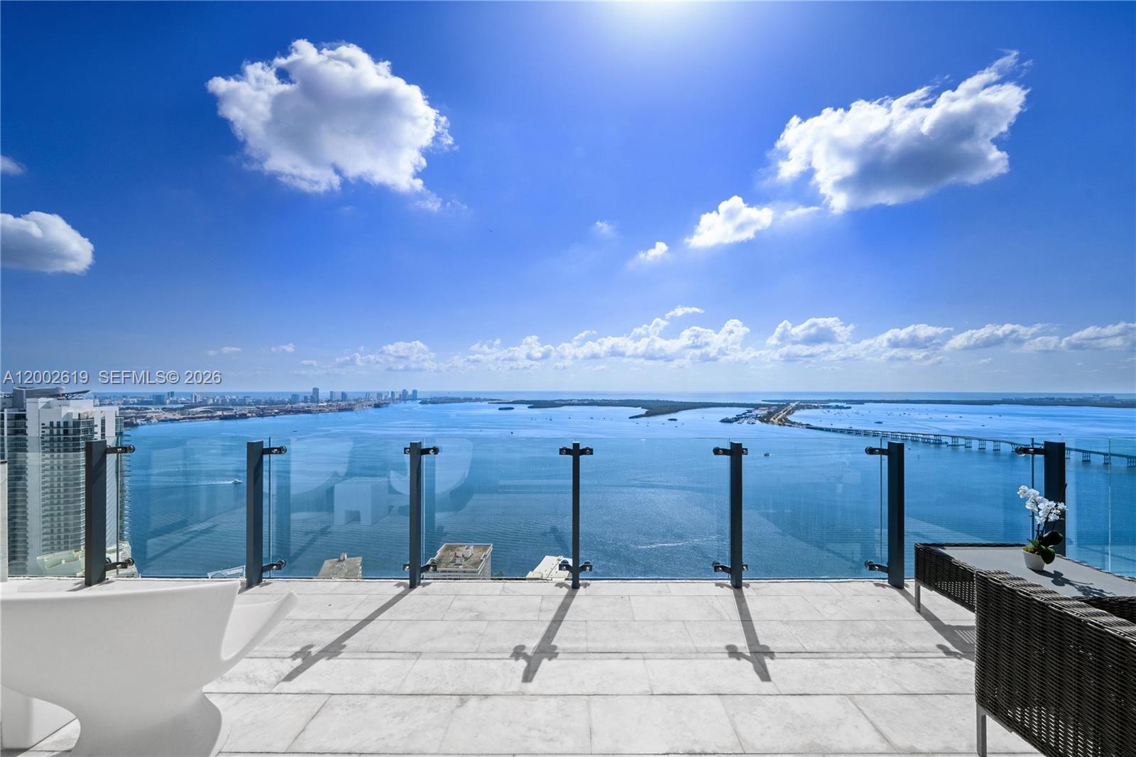 A balcony with glass railings overlooks a bay, a bridge, and a distant city skyline — 1451 Brickell Ave # 5101, Miami FL 33131, MIAMI, FL