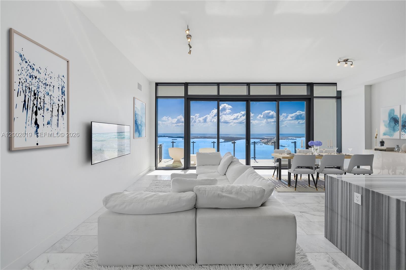 A bright living and dining area features white furniture, marble floors, and floor-to-ceiling ocean views — 1451 Brickell Ave # 5101, Miami FL 33131, MIAMI, FL