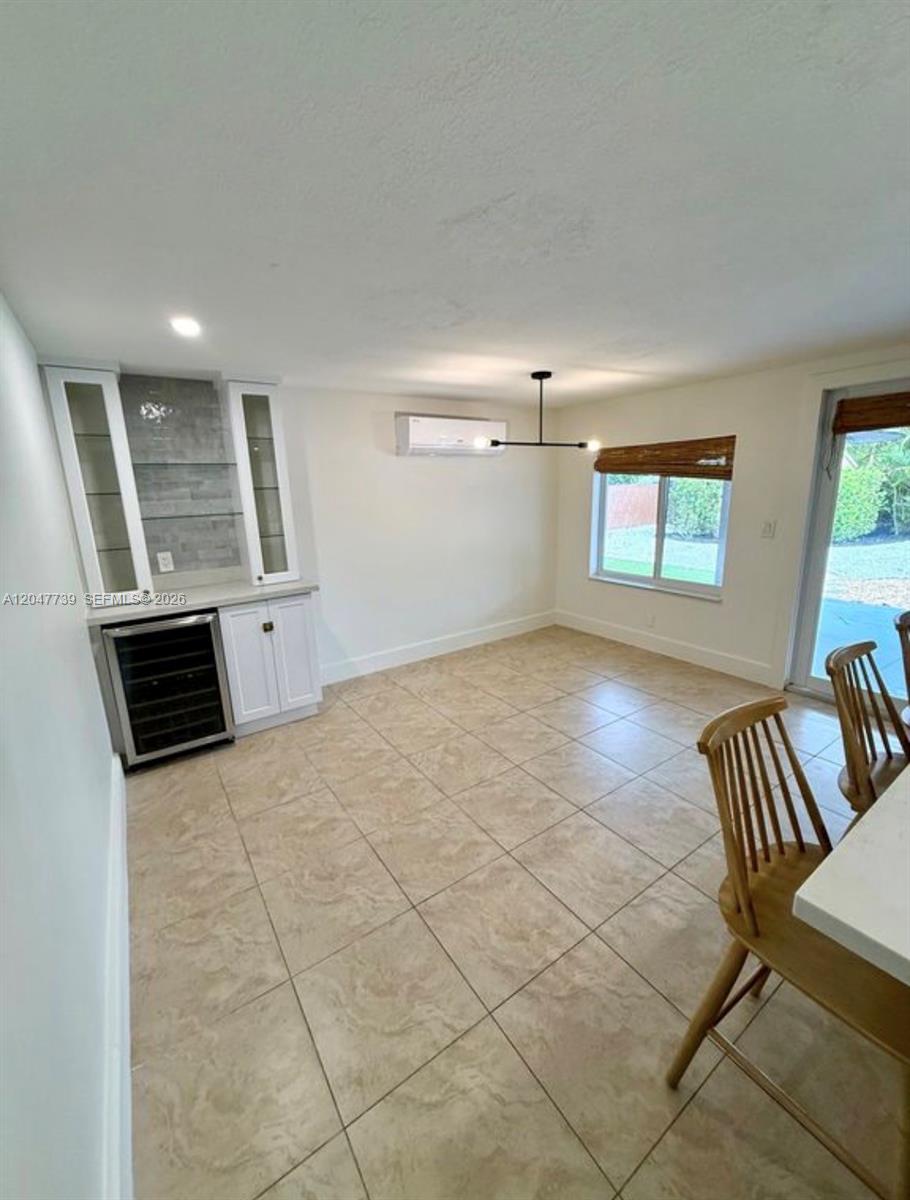A dining room features tile flooring, a built-in bar with a wine cooler, and windows — 670 E 58th St, Hialeah FL 33013, HIALEAH, FL