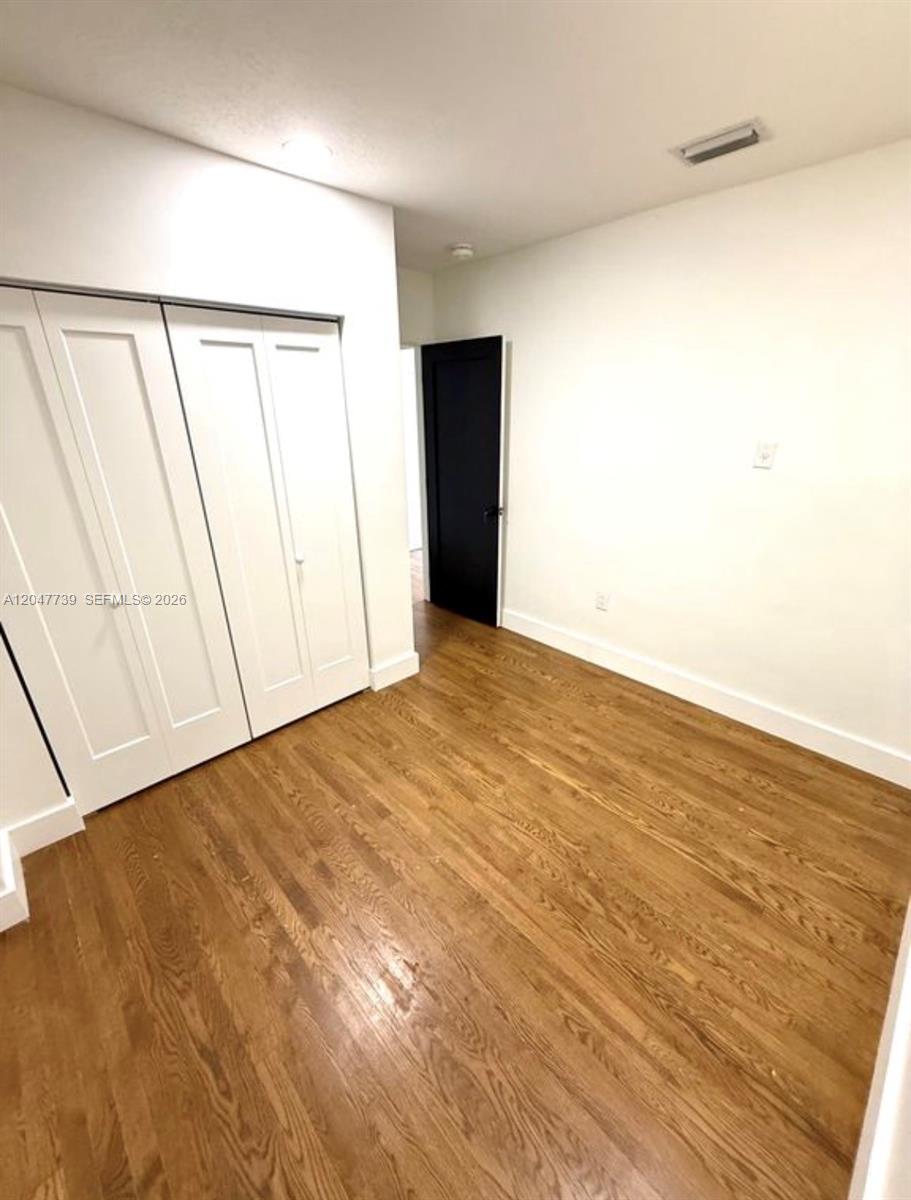 An empty room features white walls, hardwood flooring, and a white double-door closet — 670 E 58th St, Hialeah FL 33013, HIALEAH, FL
