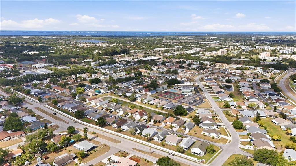An aerial view shows a suburban neighborhood with houses, a community pool, and tennis courts — 4006 W 37TH STREET COURT W, BRADENTON, FL