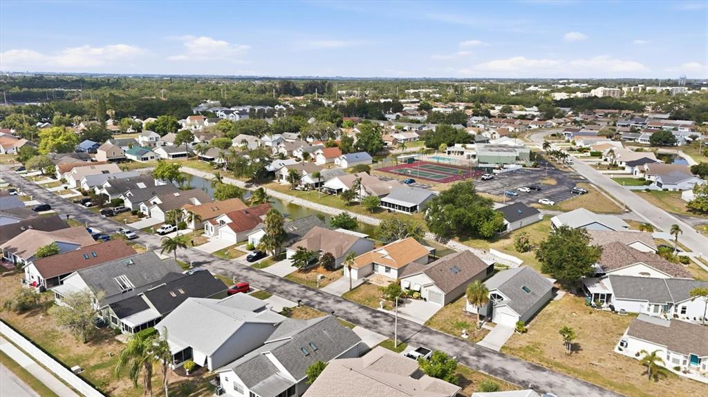 An aerial view shows a suburban neighborhood with single-family homes, a canal, and tennis courts — 4006 W 37TH STREET COURT W, BRADENTON, FL