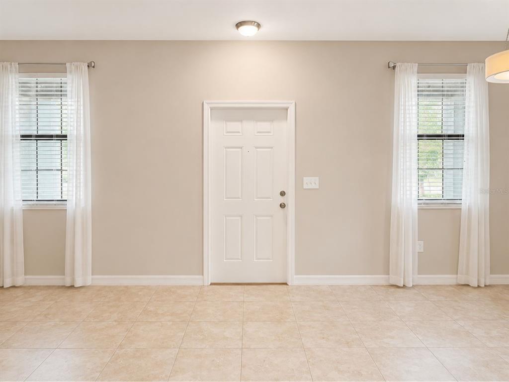 A room with beige walls, tile flooring, a central white door, and two windows — 17575 BRIGHTON LAKE ROAD, LAND O LAKES, FL
