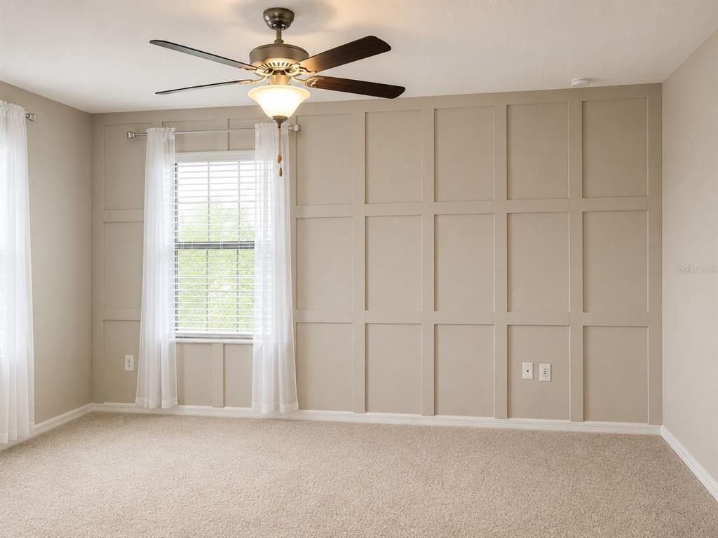 A bedroom features beige walls with grid molding, a ceiling fan, and carpeted flooring — 17575 BRIGHTON LAKE ROAD, LAND O LAKES, FL