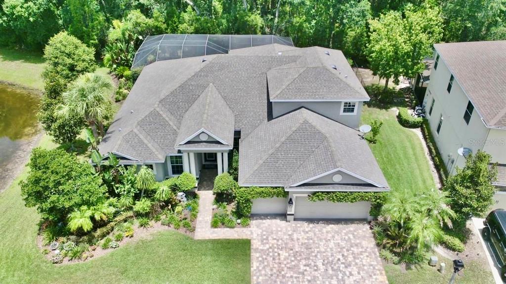 An aerial view of a single-family home with a paved driveway and a screened pool — 15321 AZRA DRIVE, ODESSA, FL