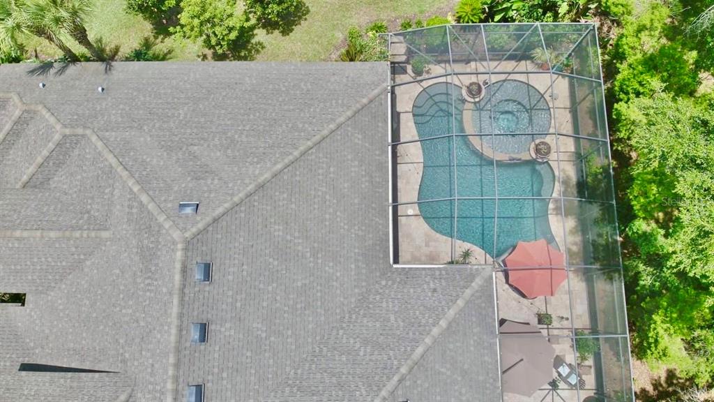 An aerial view shows a shingled roof and a screened-in pool area with a spa — 15321 AZRA DRIVE, ODESSA, FL