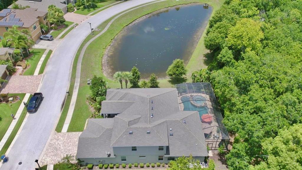 An aerial view shows a house with a screened-in pool, a pond, and surrounding trees — 15321 AZRA DRIVE, ODESSA, FL