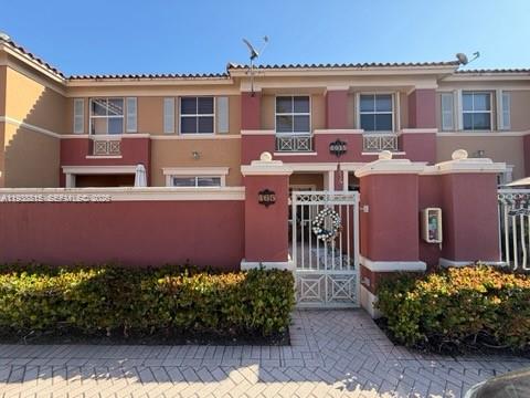 A two-story residential building features a terracotta-colored exterior, a gated entrance, and a landscaped hedge — 6015 NW 116th Pl # 465, Doral FL 33178, DORAL, FL