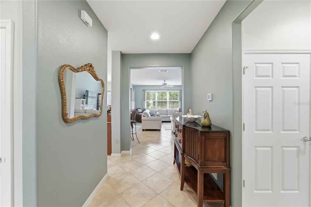 A hallway with light green walls, tile flooring, a gold mirror, and a wooden console table — 212 GRANADA LANE, DAVENPORT, FL
