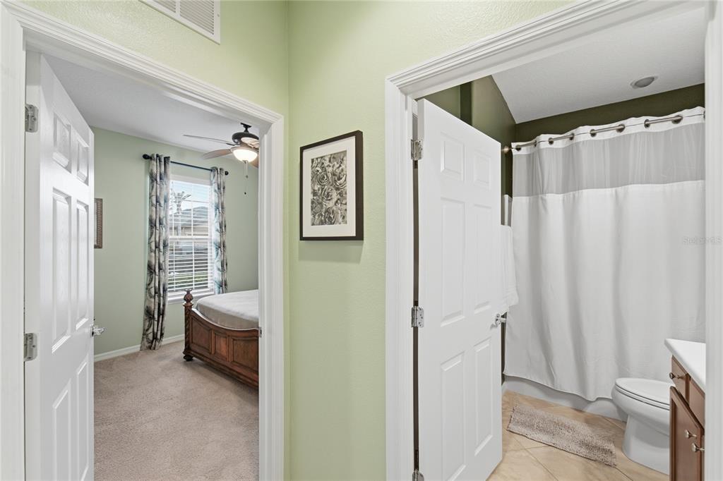 A hallway with light green walls leads to a bedroom on the left and bathroom — 212 GRANADA LANE, DAVENPORT, FL