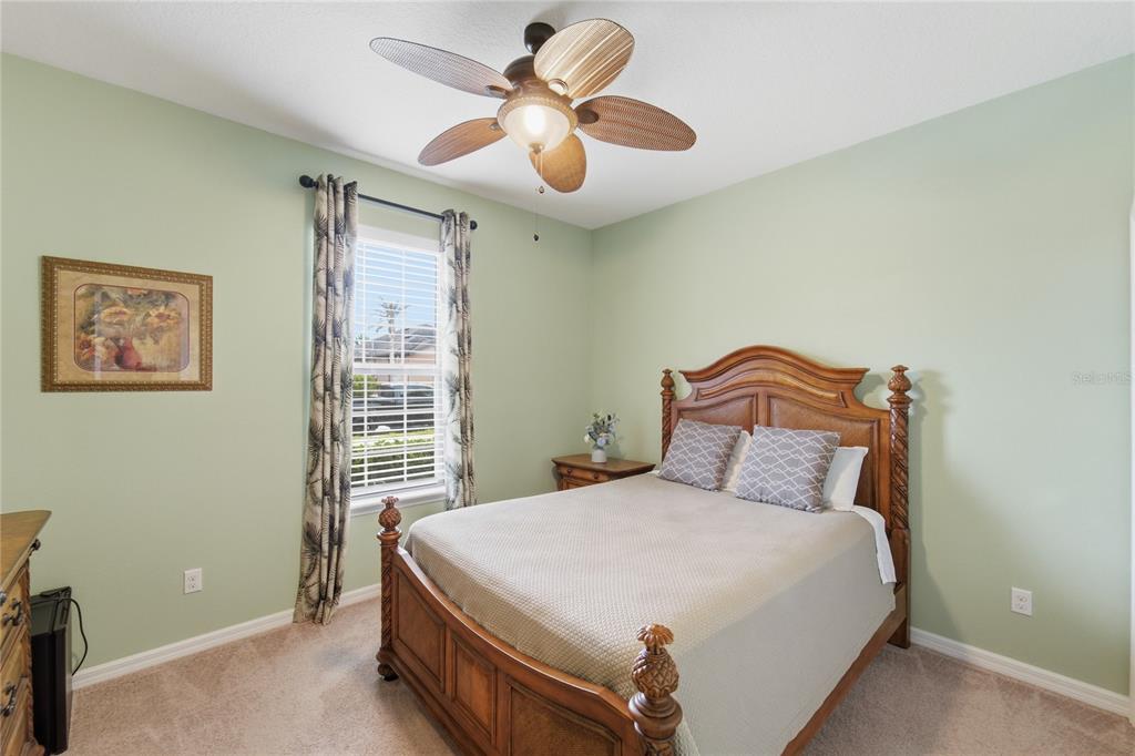 A bedroom features light green walls, a wooden bed frame, and a ceiling fan — 212 GRANADA LANE, DAVENPORT, FL