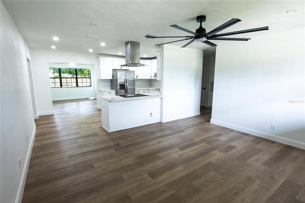A kitchen with white cabinets and a stainless steel range hood overlooks a living area — 4104 W WISCONSIN AVENUE, TAMPA, FL