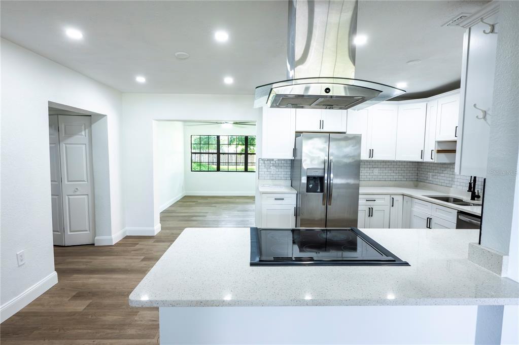 A modern kitchen features white cabinets, stainless steel appliances, and a quartz-topped island — 4104 W WISCONSIN AVENUE, TAMPA, FL