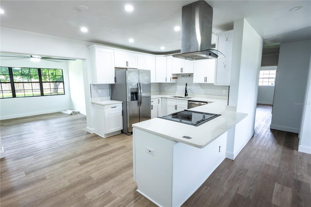 A modern kitchen features white cabinets, stainless steel appliances, a center island, and wood-look flooring — 4104 W WISCONSIN AVENUE, TAMPA, FL