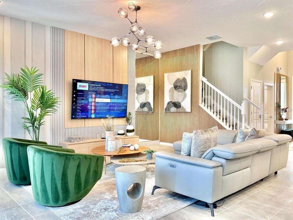 A living room features a slatted wood accent wall, a modern chandelier, and green chairs — 10012 VOYAGER WAY, ORLANDO, FL