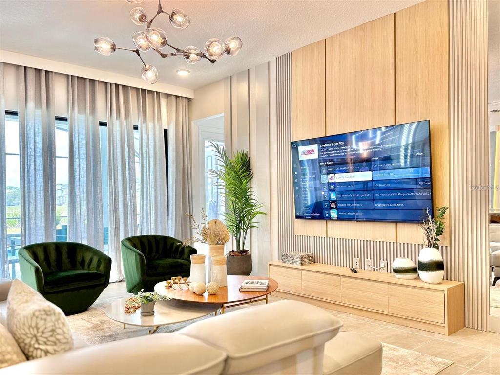 A modern living room features green velvet chairs, a wood media console, and slat wall paneling — 10012 VOYAGER WAY, ORLANDO, FL