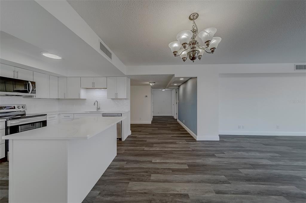 A modern kitchen with white cabinets and a peninsula overlooks an open-concept living area — 100 OAKMONT LANE UNIT 504, BELLEAIR, FL