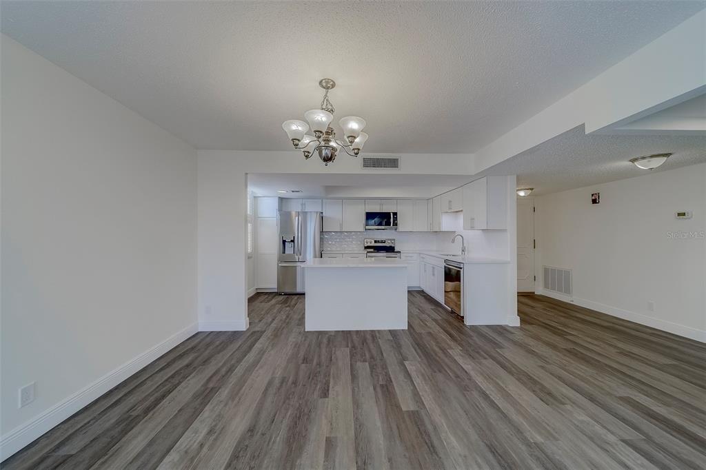 A kitchen with white cabinets, stainless steel appliances, and an island, viewed from a room — 100 OAKMONT LANE UNIT 504, BELLEAIR, FL