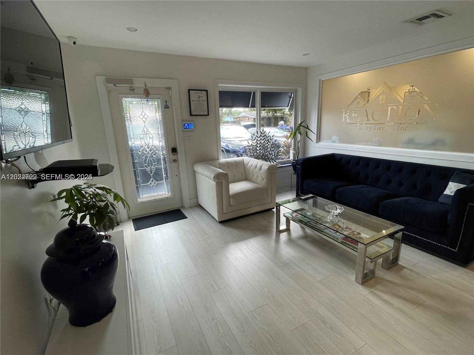 A waiting area features light wood flooring, a dark blue sofa, and a white armchair — 1640 N 70th Way, Hollywood FL 33024, HOLLYWOOD, FL