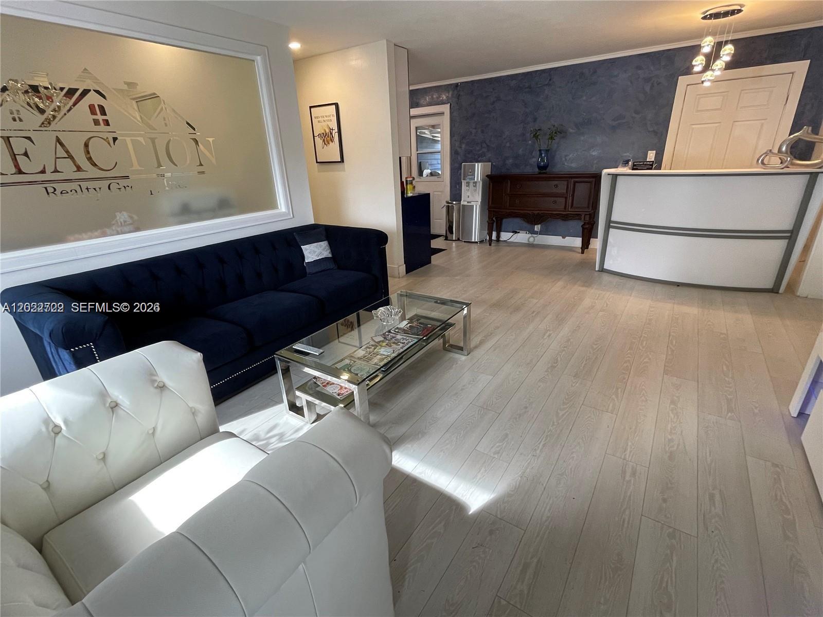A modern office reception area features a navy sofa, white armchair, and light wood flooring — 1640 N 70th Way, Hollywood FL 33024, HOLLYWOOD, FL