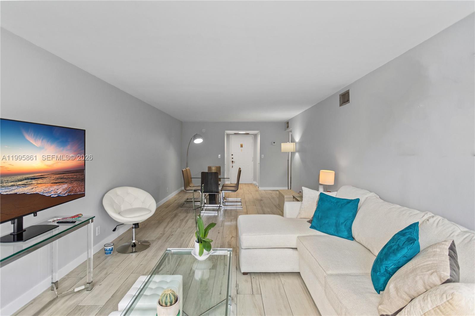 A living room features light wood-look flooring, a sectional sofa, and a dining area — 600 Parkview Dr # 204, Hallandale Beach FL 33009, HALLANDALE BEACH, FL