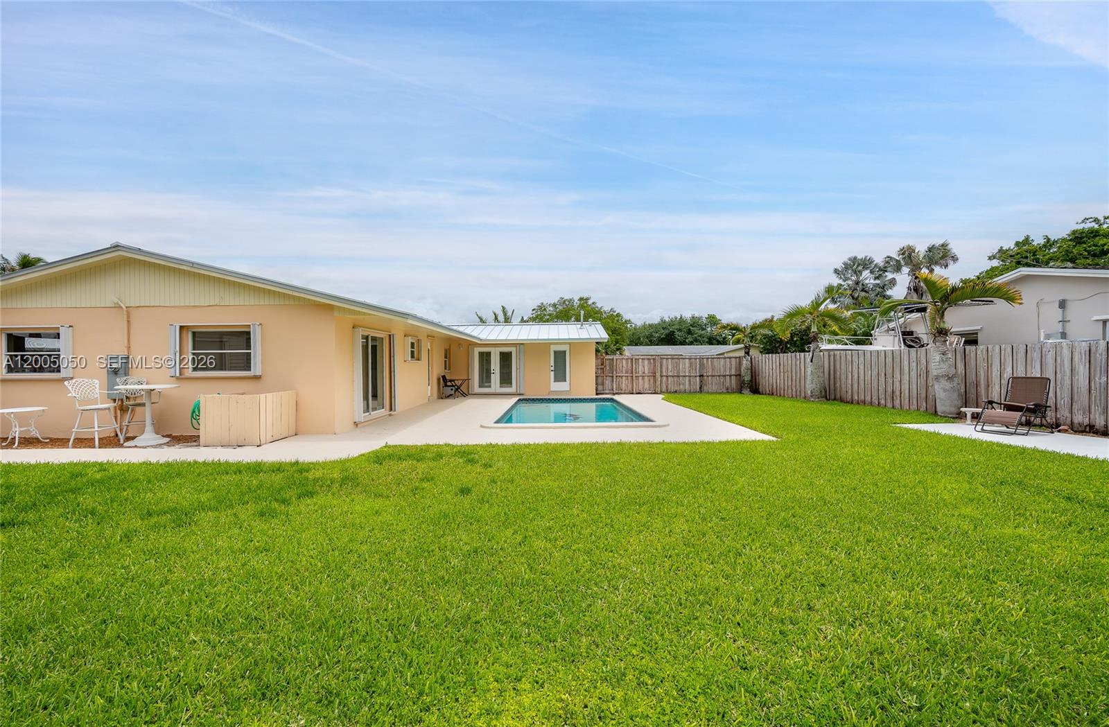 A backyard features a swimming pool, a grassy lawn, and a light-colored house exterior — 9411 SW 185th Ter, Cutler Bay FL 33157, CUTLER BAY, FL
