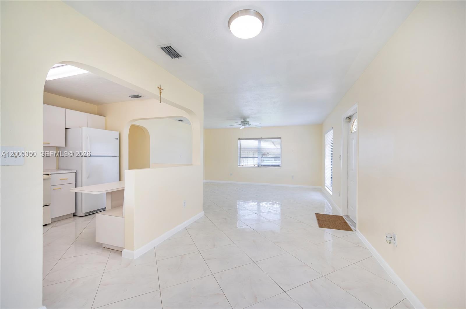 An open-concept living area features light-colored tile flooring, cream walls, and an adjacent kitchen — 9411 SW 185th Ter, Cutler Bay FL 33157, CUTLER BAY, FL