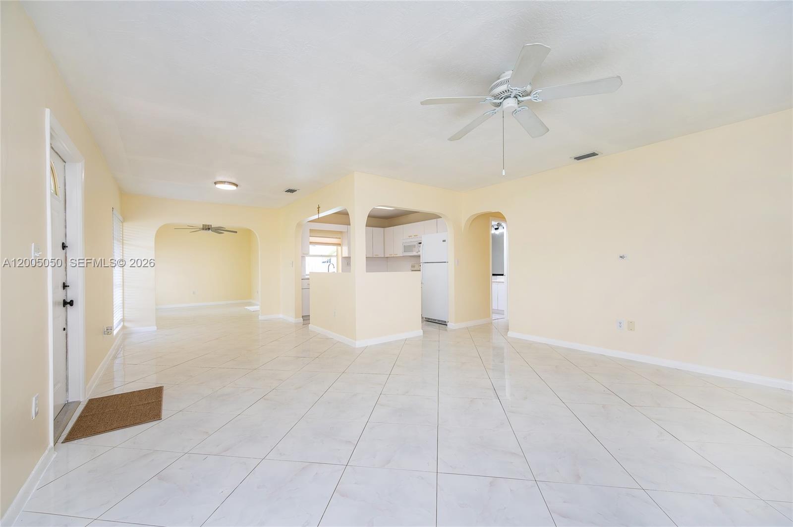 An open-concept living area features light-colored tile flooring, pale yellow walls, and arched doorways — 9411 SW 185th Ter, Cutler Bay FL 33157, CUTLER BAY, FL