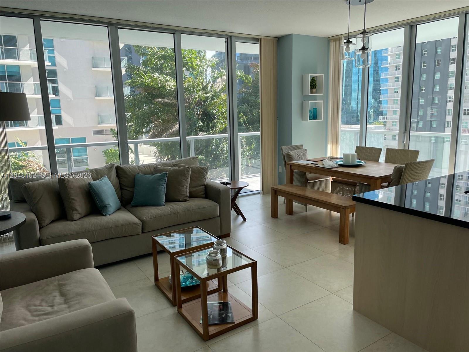 A living and dining area features floor-to-ceiling windows, tile flooring, and neutral-toned furniture — 1111 SW 1st Ave, Miami FL 33130, MIAMI, FL