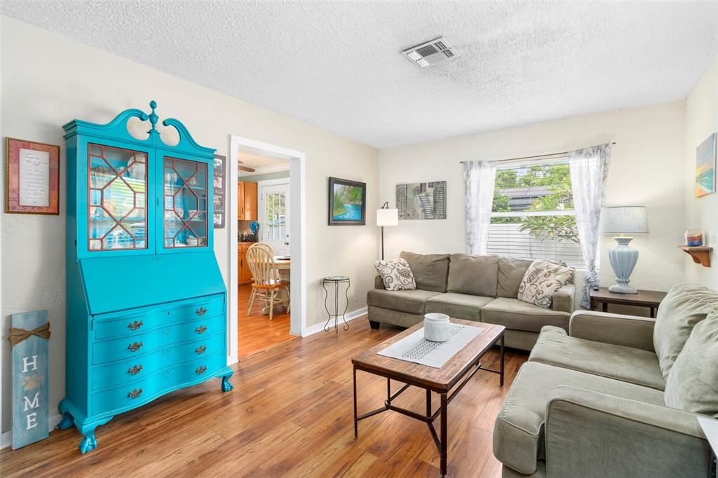 A living room features a bright blue hutch, two beige sofas, and wood-look flooring — 6030 62ND STREET N, ST PETERSBURG, FL
