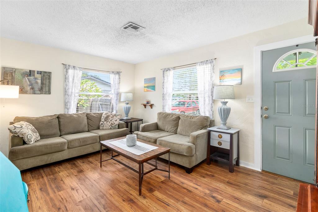 A living room features two tan sofas, a coffee table, and wood-look flooring — 6030 62ND STREET N, ST PETERSBURG, FL
